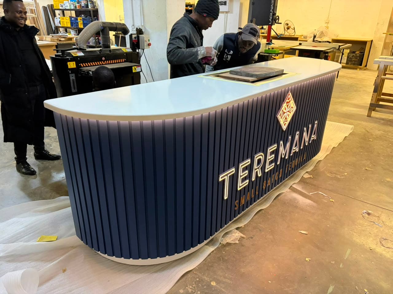 The fluted, backlit Teremana counter getting finishing touches from the crew in the workshop